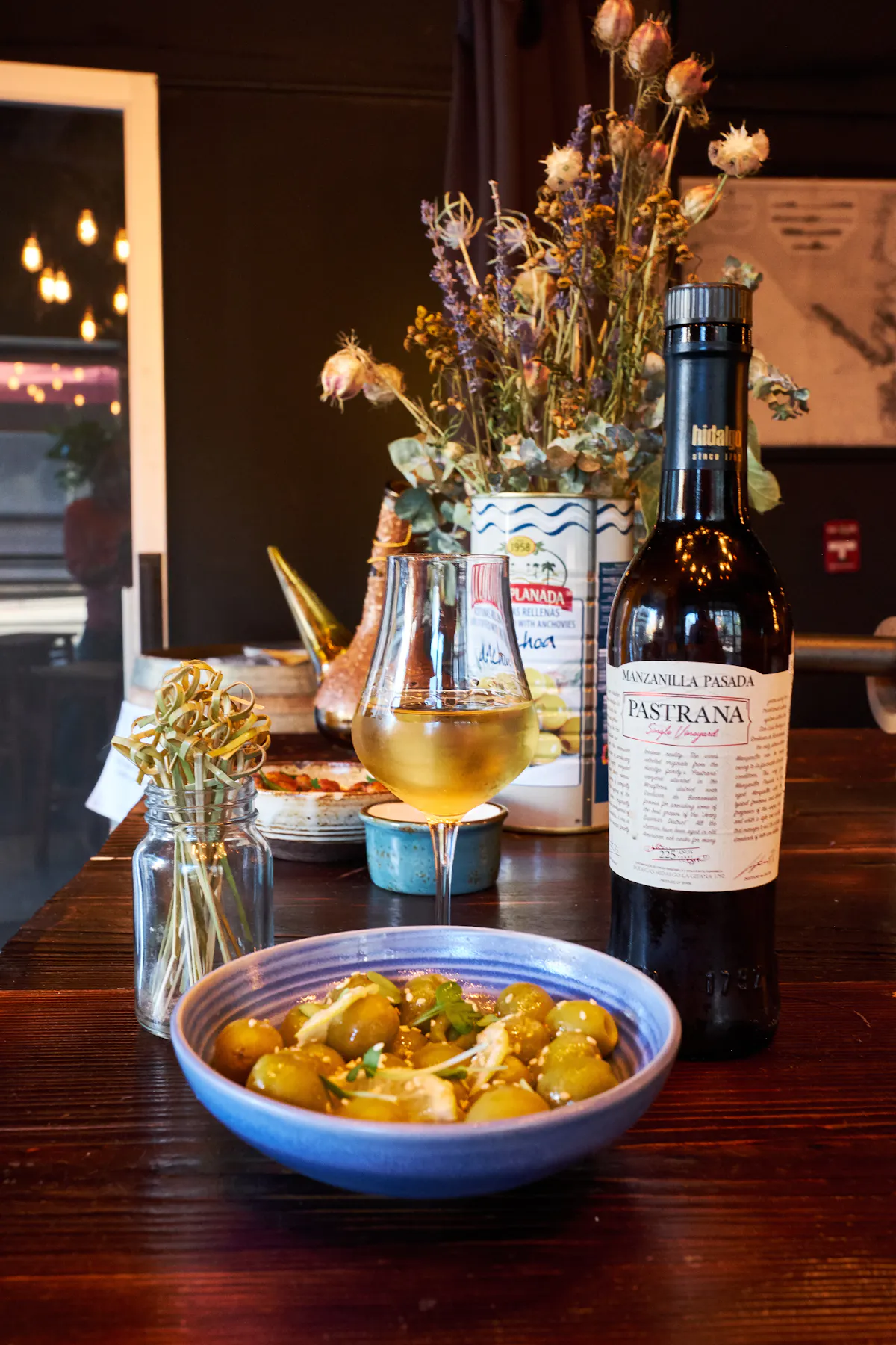 a bottle and glass of wine and a bowl of food on a table